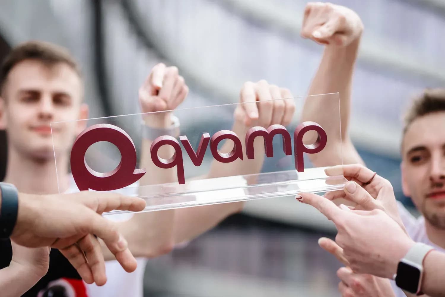 Ruky tímu Qvampu držia logo Qvamp